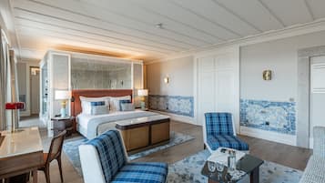 A hotel room with a large bed, a desk, a chair, a sofa, and a coffee table.