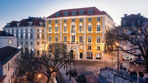 Ein mehrgeschossiges Gebäude mit einem zentralen Eingang, großen Fenstern und einem roten Ziegeldach.