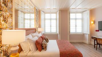 A hotel room with a large bed, a desk, and two windows.