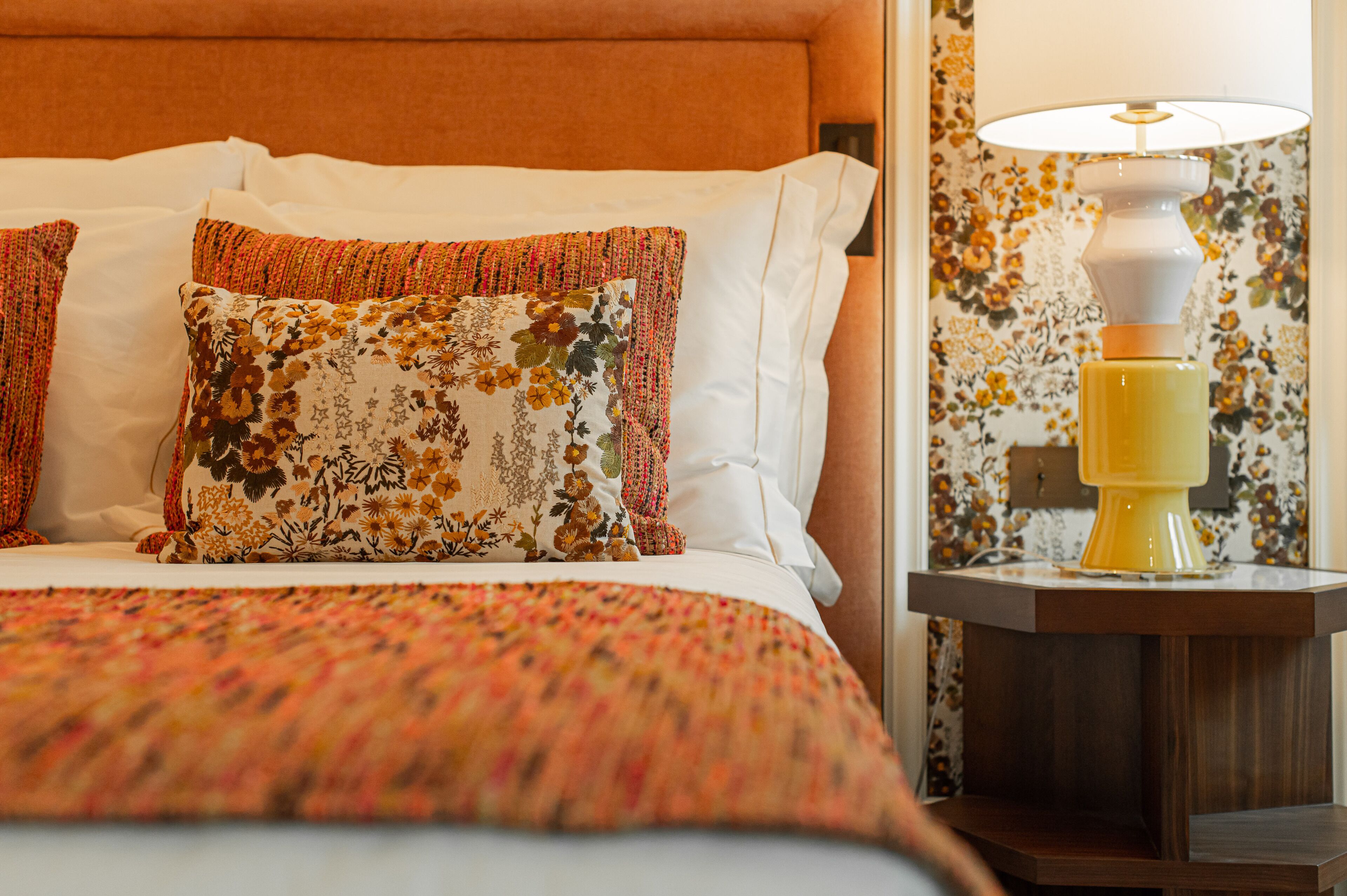 A neatly made bed with floral-patterned pillows and a patterned bedspread.