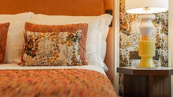 A neatly made bed with floral-patterned pillows and a patterned bedspread.