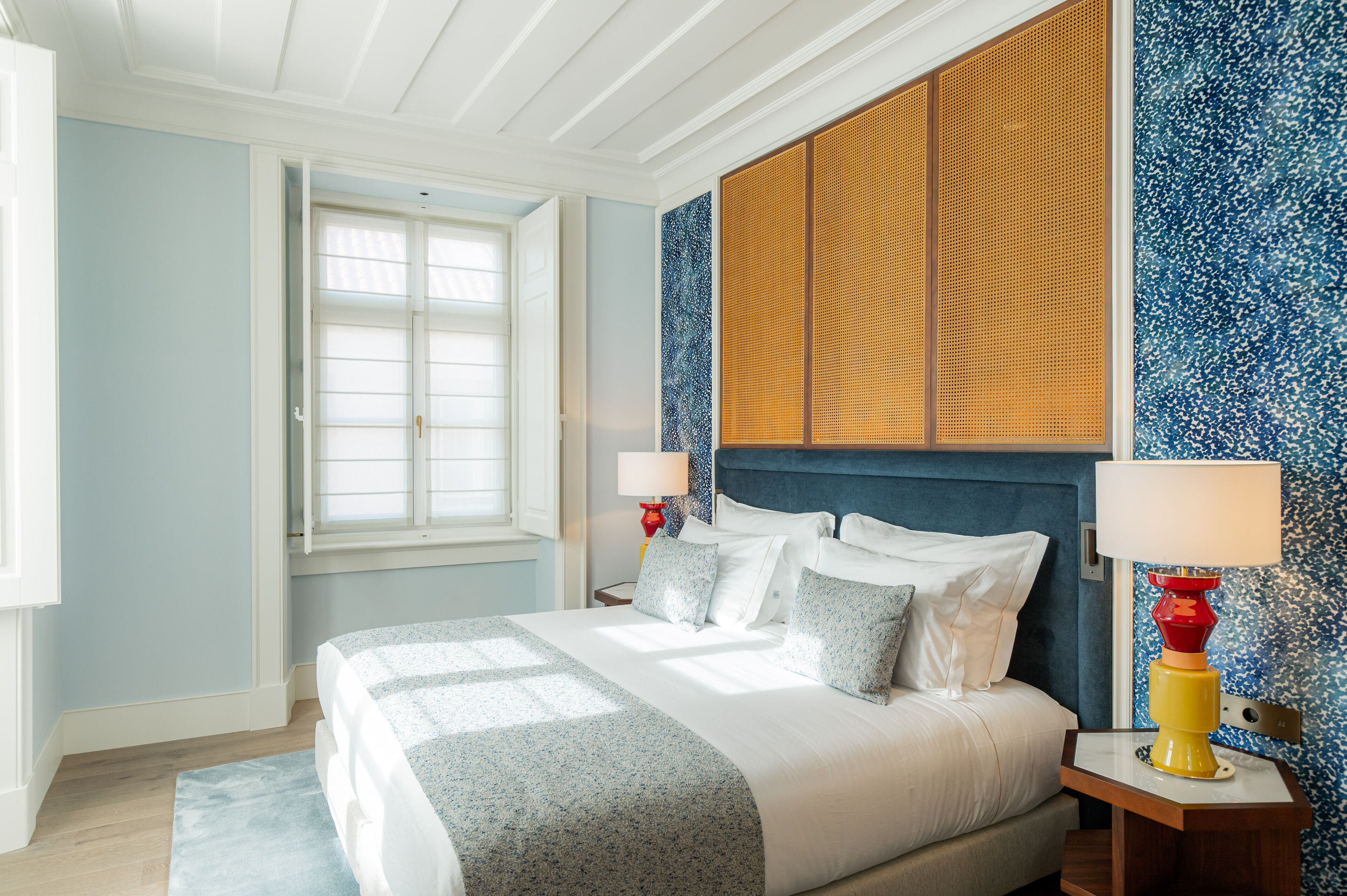 A neatly arranged bedroom with a bed, bedside lamps, and a window.