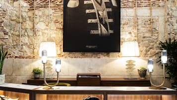 Una habitación con pared de piedra, un retrato enmarcado y una vitrina con diversos objetos.