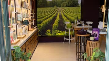 A boutique store with a large vineyard mural, a reception area, and a counter displaying products.