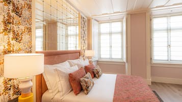 A hotel room with a large bed, floral wallpaper, and a view of the city.
