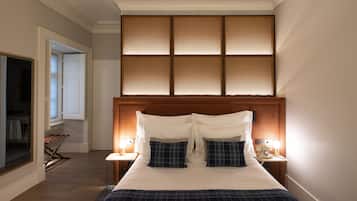Een netjes ingerichte hotelkamer met een groot bed, een houten hoofdbord en uitzicht door een raam met luxaflex.