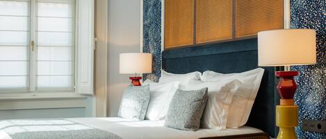 A hotel room with a bed, two bedside tables with lamps, a window, and a textured wall.