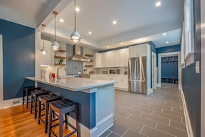 A modern kitchen with a central island, bar stools, and stainless steel appliances.
