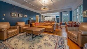 A spacious living room with leather sofas, a wooden coffee table, and a large patterned rug.