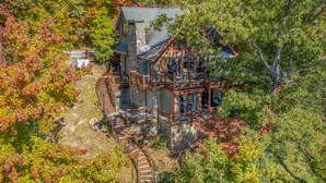Une maison à étages avec une façade en pierre, une terrasse en bois et un escalier menant à un porche.