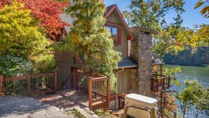 Une cabane avec une façade en pierre, une terrasse en bois et une vue sur un lac.
