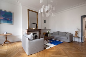 A modern living room with a grey sofa, a coffee table, and a fireplace. - The Demoiselles at Versailles, Residence of the Swiss (Versailles)