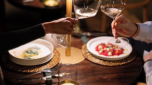 A dining table with plates of food, wine glasses, and a candle. - Vico Milano (Milan)