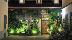 A hotel entrance with a covered patio, potted plants, and a bike parking area. - Vico Milano (Milan)