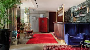 A modern living room with a red rug, a blue sofa, and a red cabinet.