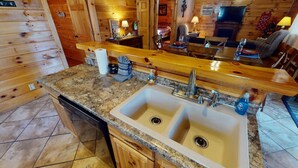 A kitchen with granite countertops, double sinks, and wooden cabinetry.