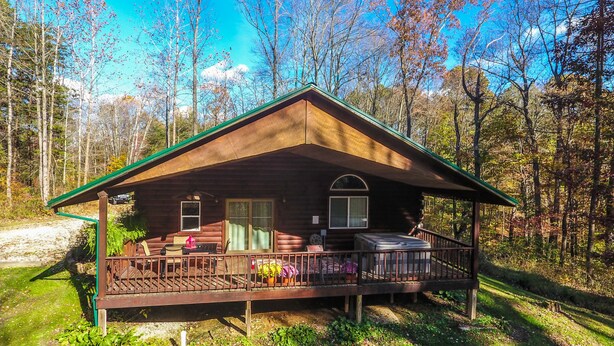 Une cabane dotée d’une véranda, d’une terrasse couverte et d’un petit garage attenant.