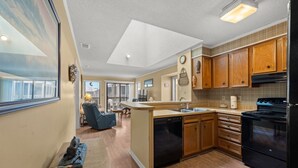 A modern kitchen with wooden cabinets, a black refrigerator, and a dishwasher.