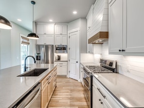 A modern kitchen with stainless steel appliances, wooden cabinets, and a central island.
