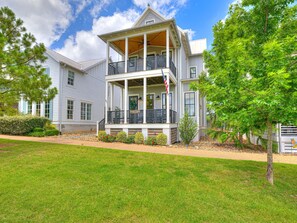 A two-story house with a covered porch, a flag, and a sign that reads 'Gentry Gardens.'