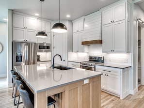 A modern kitchen with white cabinetry, stainless steel appliances, and a central island with bar stools. - Carlton Landing!  Come enjoy Greenway Getaway (Eufaula)