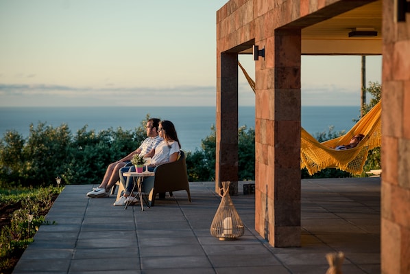 A couple sitting at an outdoor table with a view of the ocean.