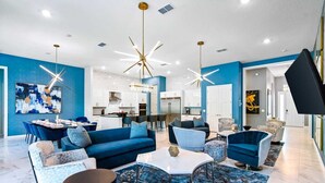 A modern living room with a blue sofa set, a round coffee table, and a dining area with a white table and chairs.