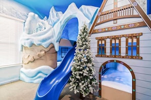 A children's play area with a blue slide, a snow-covered play structure, and a small Christmas tree. - Grand Home w Sports Simulator, Bowling, Gym, Arcade, Pirate Theme BR, Near Parks (Davenport)
