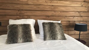 A bed with white bedding and two large, fluffy pillows against a wooden wall. - 4-6 Pers apartment in the heart of the Chartreuse at the foot of the ski slopes (Sarcenas)