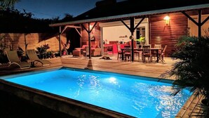 Ein Schwimmbecken mit Holzterrasse und Liegestühlen.