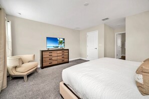 Een hotelkamer met een bed, een dressoir, een stoel en een schilderij aan de muur.
