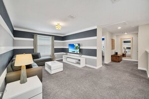 Een moderne woonkamer met een flatscreen televisie, een bank, een salontafel en een lamp.