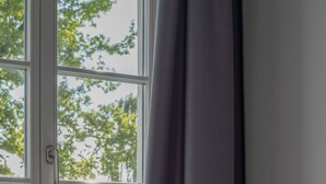 A room with a window, a blue sofa, and a decorative white object on a stand. - Exclusive with lake view, free parking space and high-quality furnishings (Tegernsee)