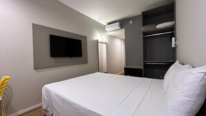 Une chambre à coucher comprenant un lit, un téléviseur fixé au mur, une armoire et un appareil de climatisation.