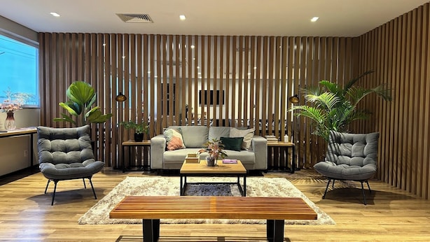 Un salon moderne comprenant un canapé, deux fauteuils, une table basse et un banc en bois.