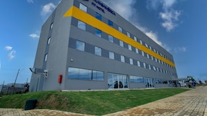 Un bâtiment moderne doté d’un toit plat, de grandes fenêtres et d’une bande jaune bien visible.