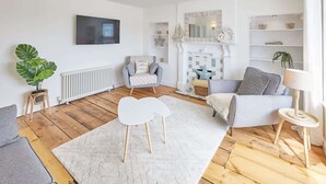 Uma sala de estar moderna com lareira, televisão e estante de livros.