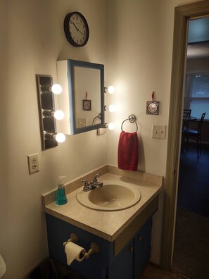 A bathroom with a sink, mirror, and lights. - Ticky's Cottage at Empire Estate (Lebanon)