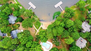 Vista aérea de una zona residencial con piscina, muelle y abundante vegetación.