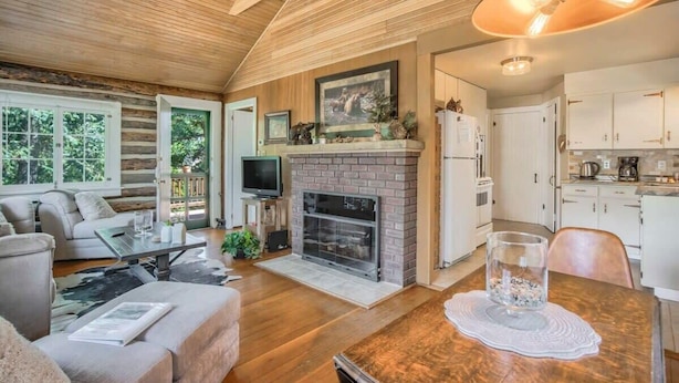 Una sala de estar acogedora con chimenea, televisor y comedor con mesa y sillas.