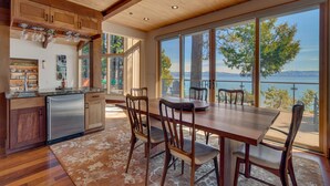 A modern kitchen with wooden cabinets, a stainless steel refrigerator, and a dining area with a large table and chairs.