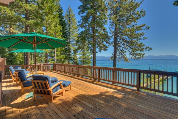 A wooden deck with outdoor seating and a view of a lake.