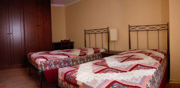 Une chambre avec deux lits, une armoire en bois et une chaise.