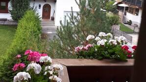 Un pueblo de montaña con casas de madera tradicionales, un jardín con flores y vistas al bosque circundante.
