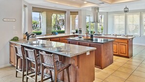 A spacious kitchen with a large island, bar stools, and a view of the outdoors. - Vineyard View by Fieldtrip 8 Bd with Infinity Pool, Hot Tub, Games (Murrieta)
