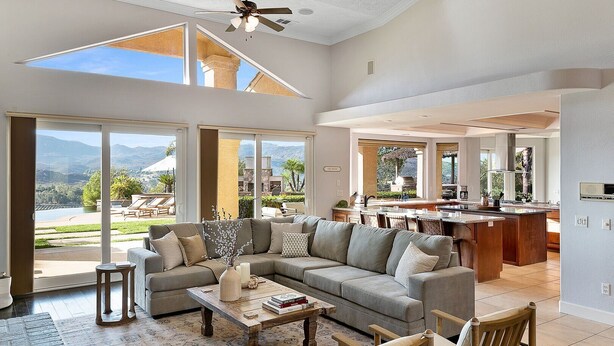 A spacious living room with a large sectional sofa, a coffee table, and a view of the outdoors. - Vineyard View by Fieldtrip 8 Bd with Infinity Pool, Hot Tub, Games (Murrieta)