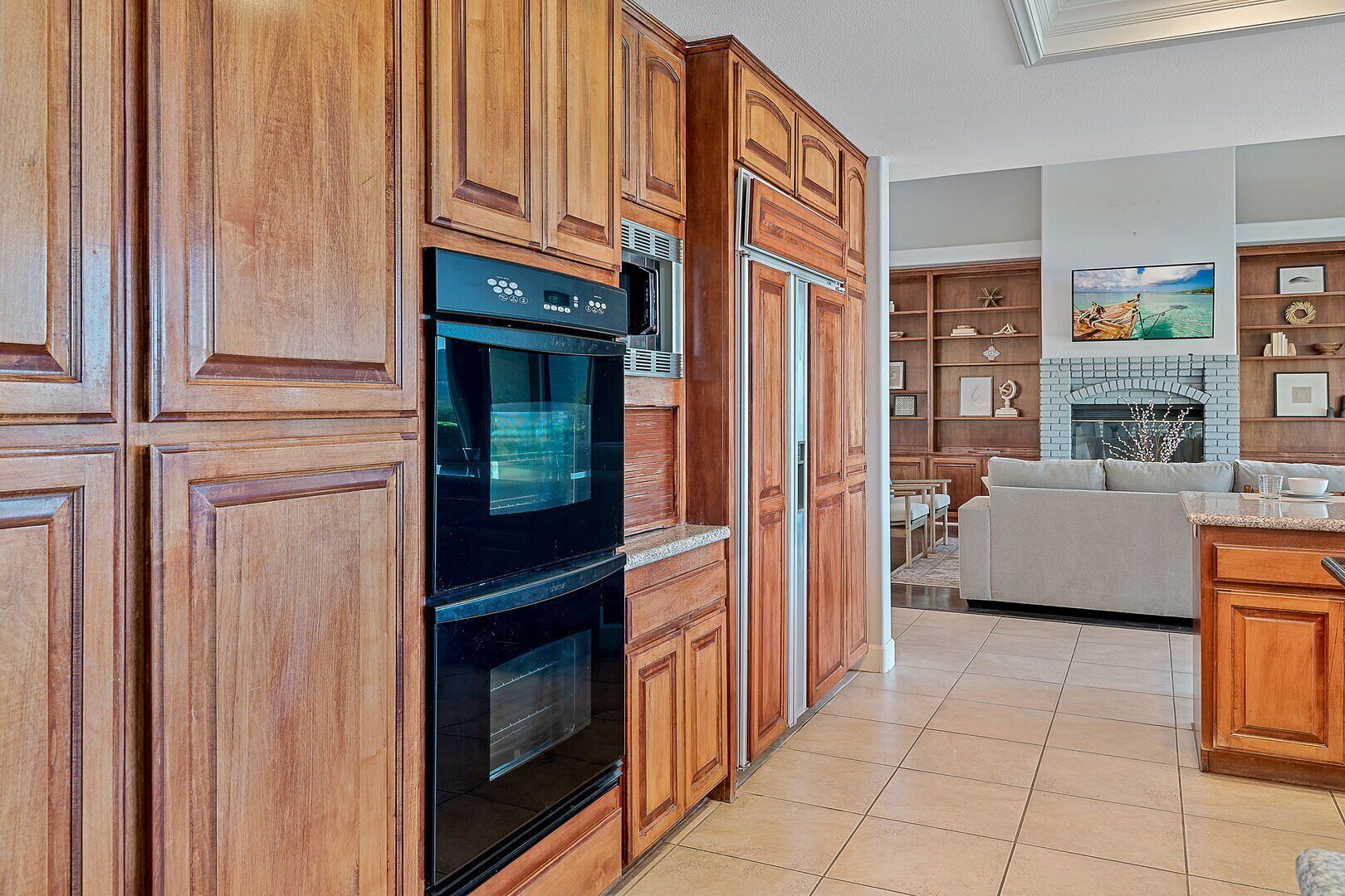 A kitchen with wooden cabinetry, a built-in oven, and a dining area with a sofa and table.
