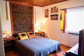 Ein Schlafzimmer mit einem großen Bett, zwei Nachttischen mit Lampen, einer Wandteppich und einem Fenster mit Vorhängen.