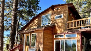 A wooden cabin with a stone staircase leading to a deck, a grill, and large windows. - Explore. Rest. Restore. (Rimforest)
