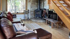 A cozy living room with a stone fireplace, leather sofa, and a wooden staircase. - Explore. Rest. Restore. (Rimforest)
